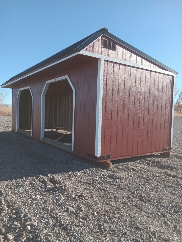 Under a clear blue sky, the Horseman - 2303 stands proudly as a red, open-sided barn structure with a sleek black roof on a gravel surface.